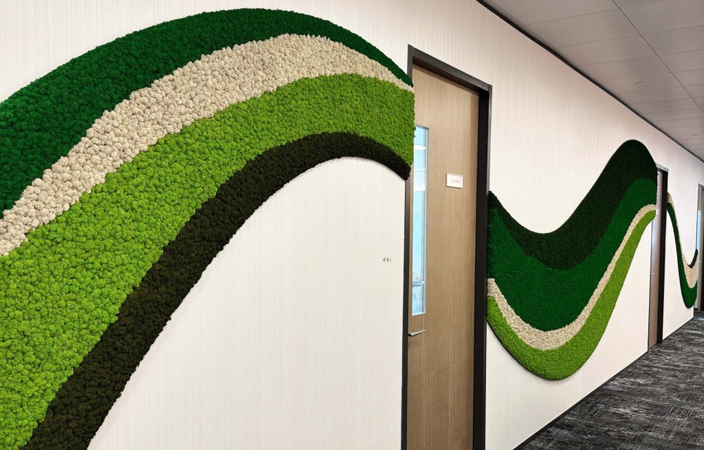 Reference image of Polarmoss Ltd. Office interior with large custom made colored moss element reaching through the whole wall. Shape of a wave. Four different colors of moss used. Produced by Polarmoss.